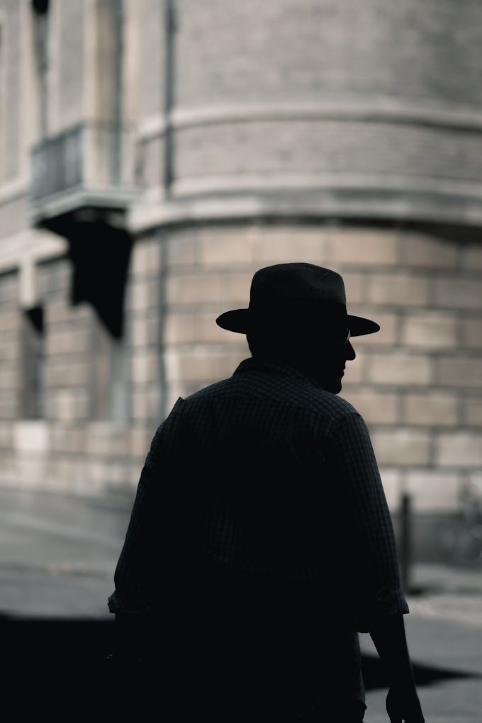 Silhouette of a private investigator walking near a building representing discreet surveillance services